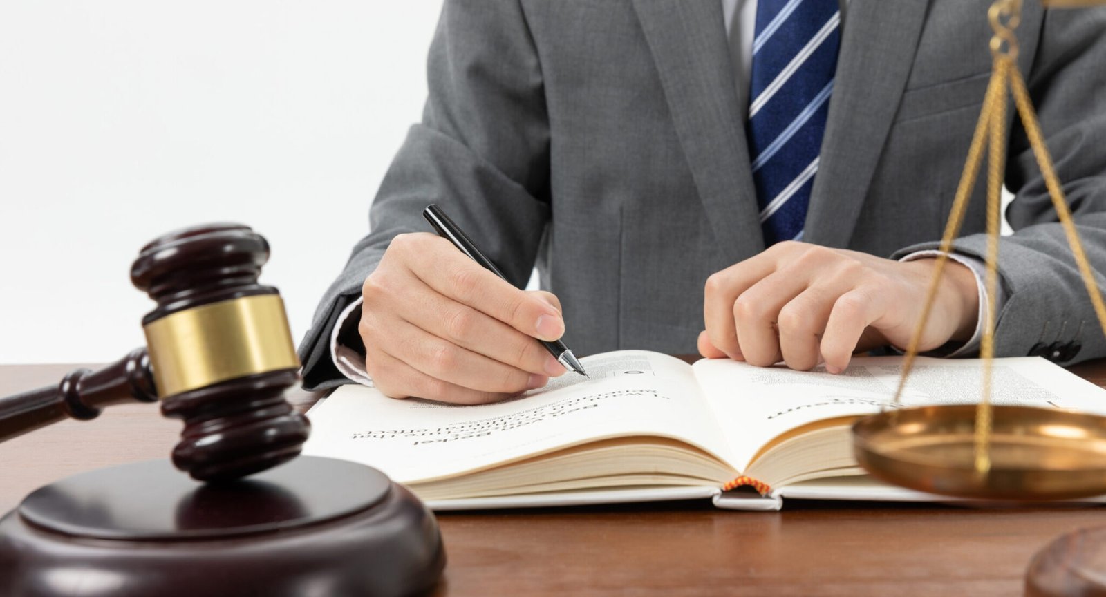 closeup-shot-person-writing-book-with-gavel-table